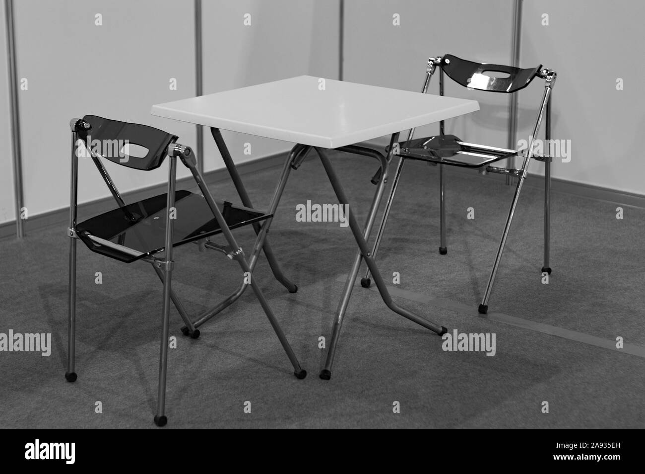 A table and two chairs in the corner of the room. Black and white shot. Side view. Stock Photo