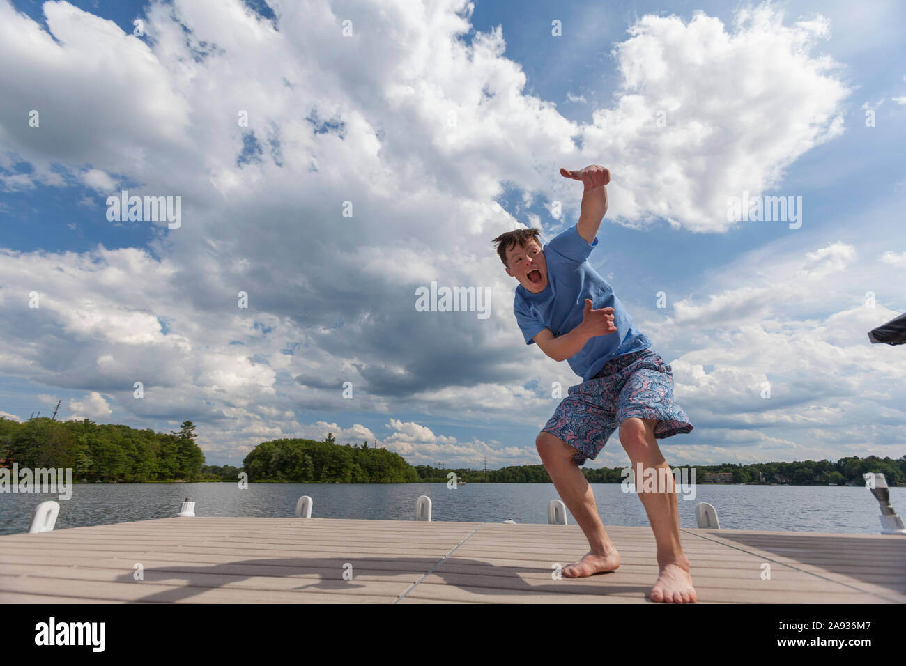 Young man with Down Syndrome playing on a dock Stock Photo