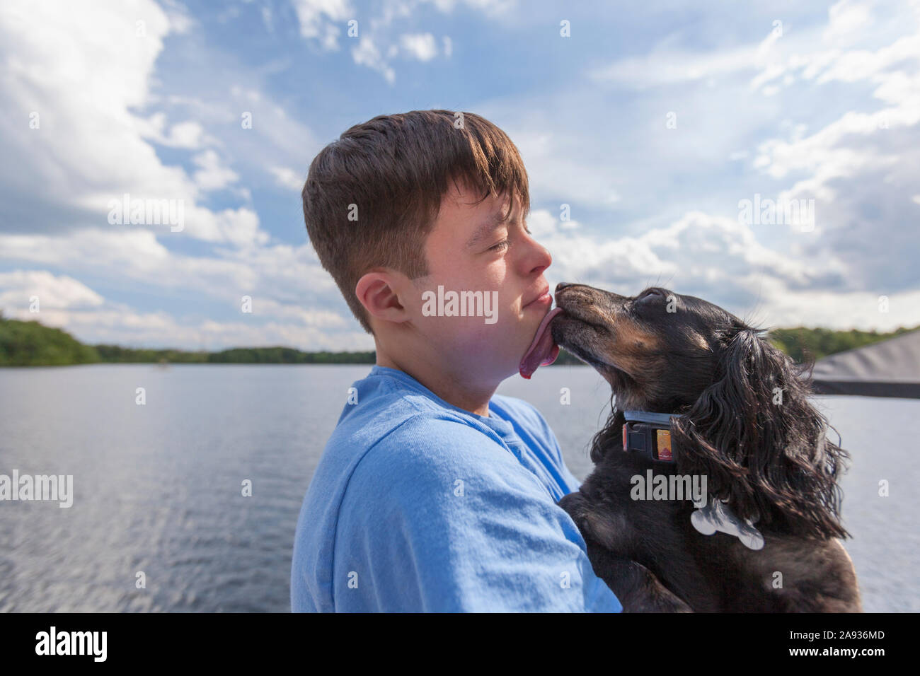 Young man with Down Syndrome playing with a dog on a dock Stock Photo