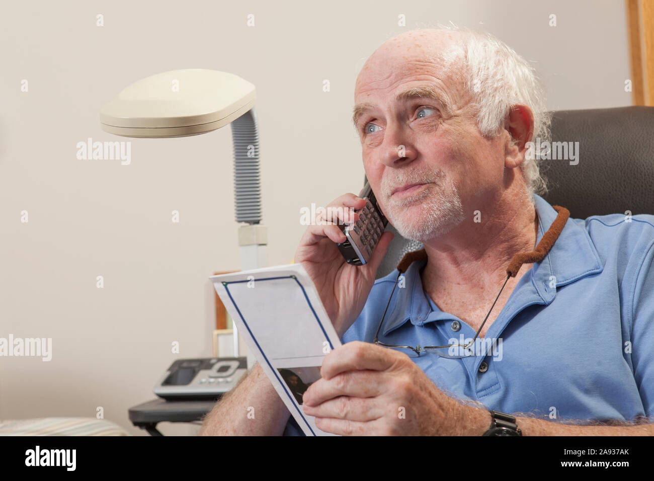 Man with Ataxia reading book and using his cell phone Stock Photo