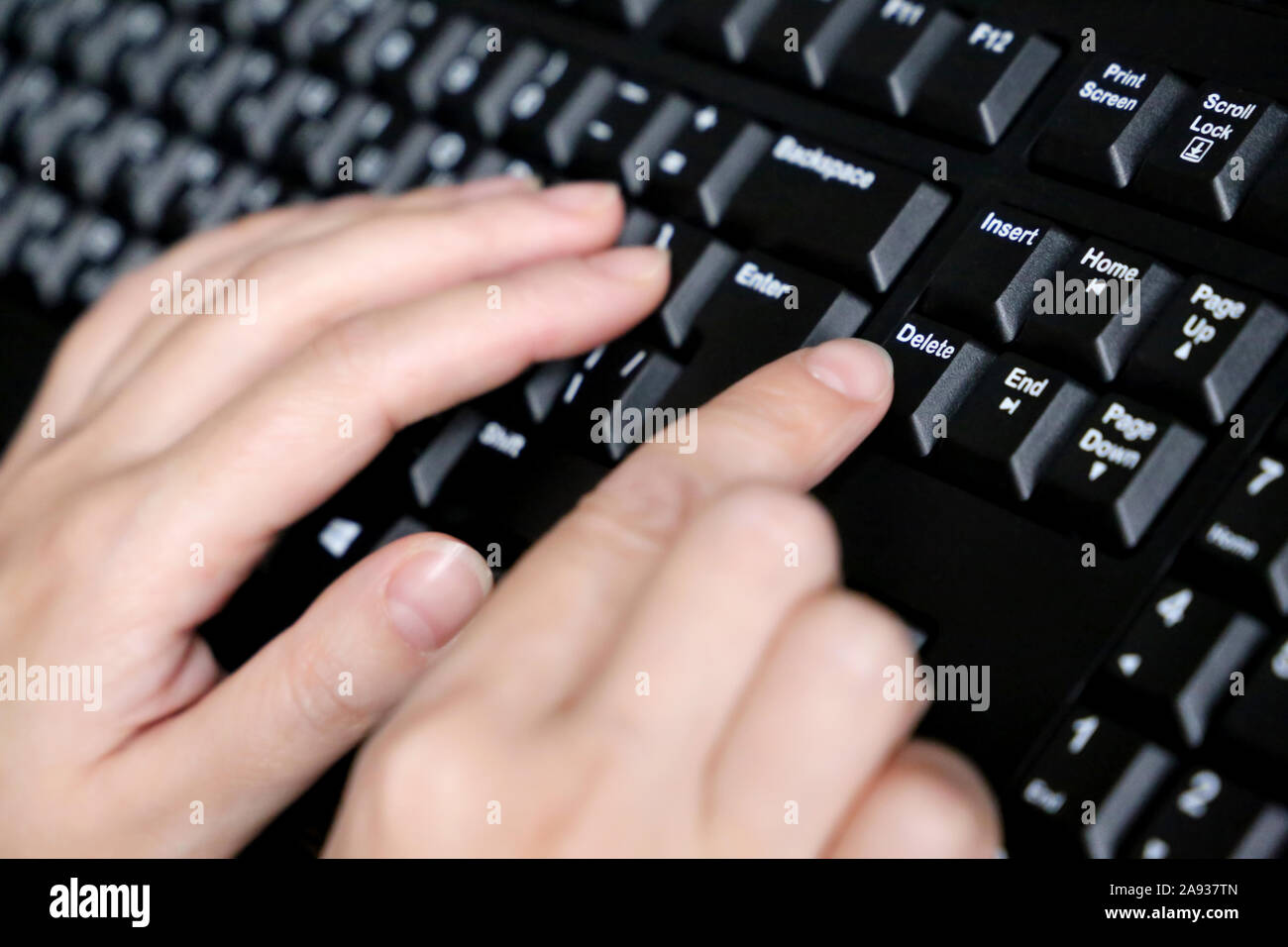 Female hands on computer keyboard close up, selective focus. Woman presses the Delete key, concept of error correction Stock Photo