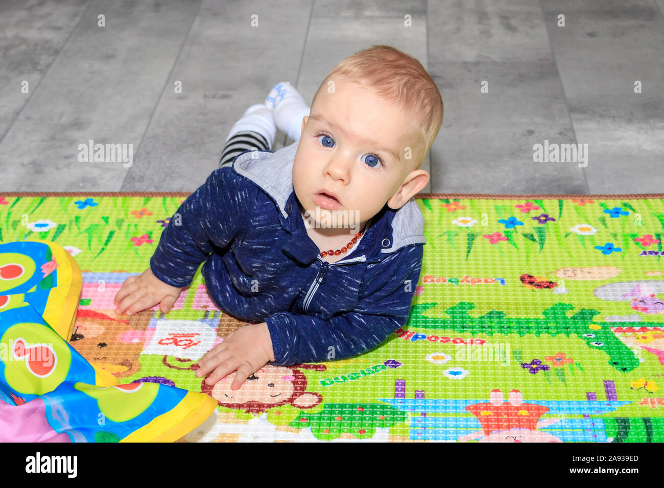 Closeup Of Happy Nine Months Baby Boy Crawling On Colorful Playmat A Nine Month Old Boy With Blond Hair And Blue Eyes Stock Photo Alamy