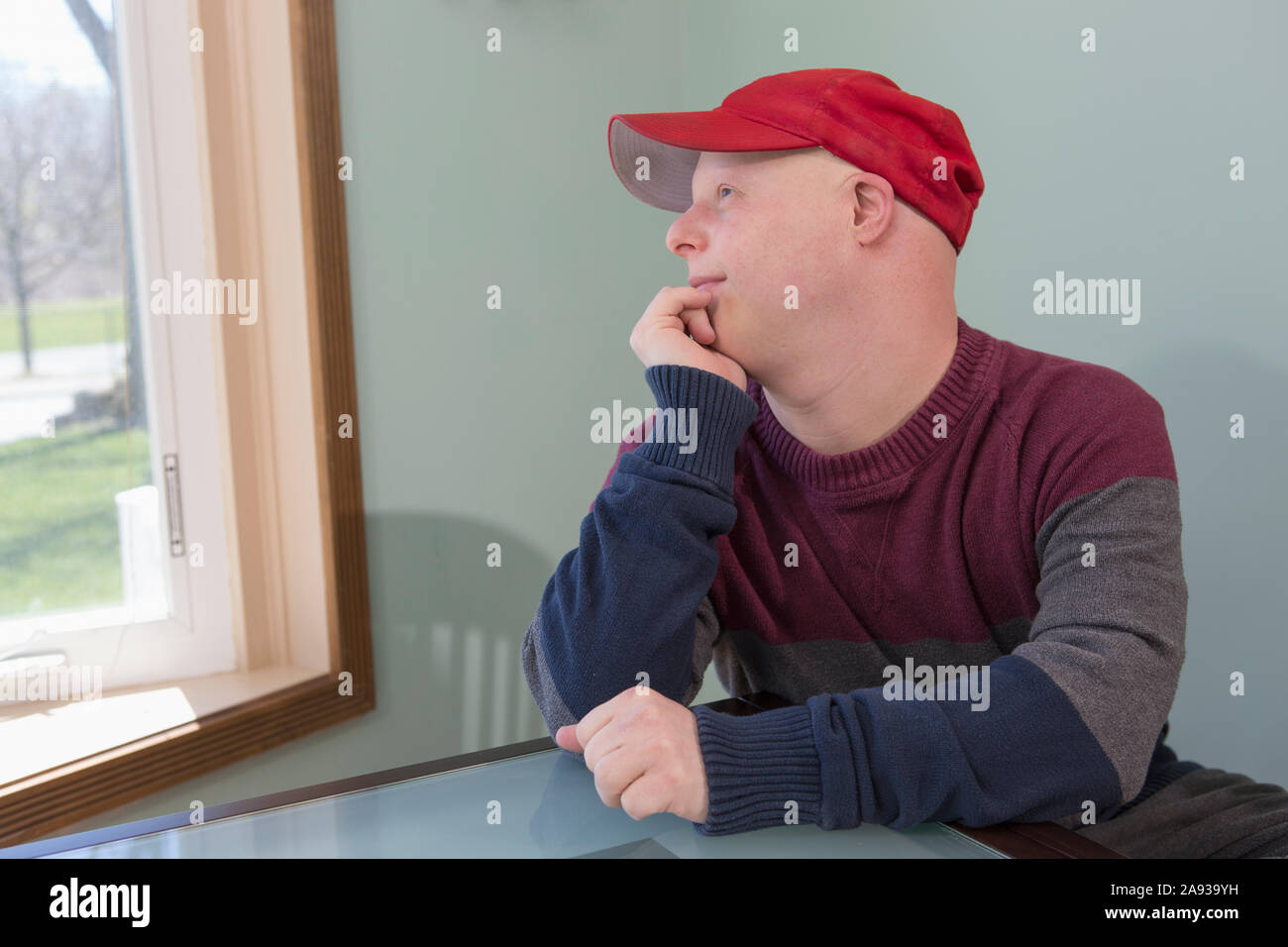 Happy young man with Down Syndrome sitting at home Stock Photo