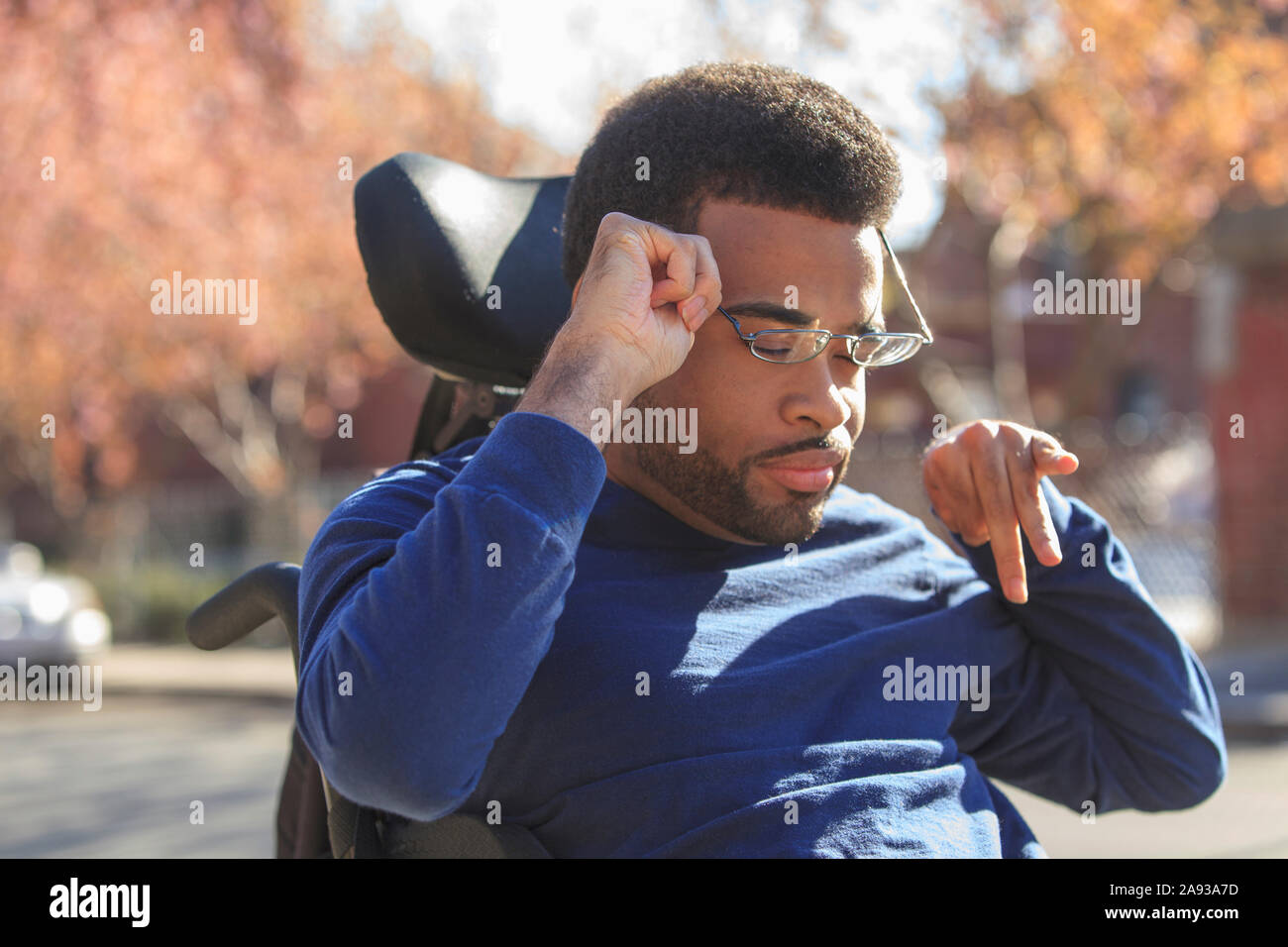 African American man with Cerebral Palsy putting on eyeglasses on his ...
