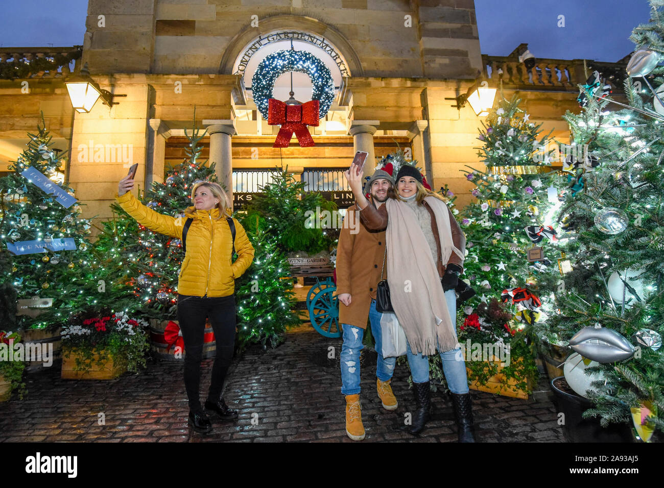 London, UK.  12 November 2019.  Tourists outside the Market Building ahead of the annual Christmas lights switch-on in Covent Garden.  Decorations include 40 large mistletoe chandeliers adorned with almost 700 glistening berries,  over 320 metres of garlands and around 100,000 pea lights suspended within the historic Market Building.  Outside, the world famous Piazza hosts London’s biggest hand-picked Christmas tree.  Credit: Stephen Chung / Alamy Live News Stock Photo