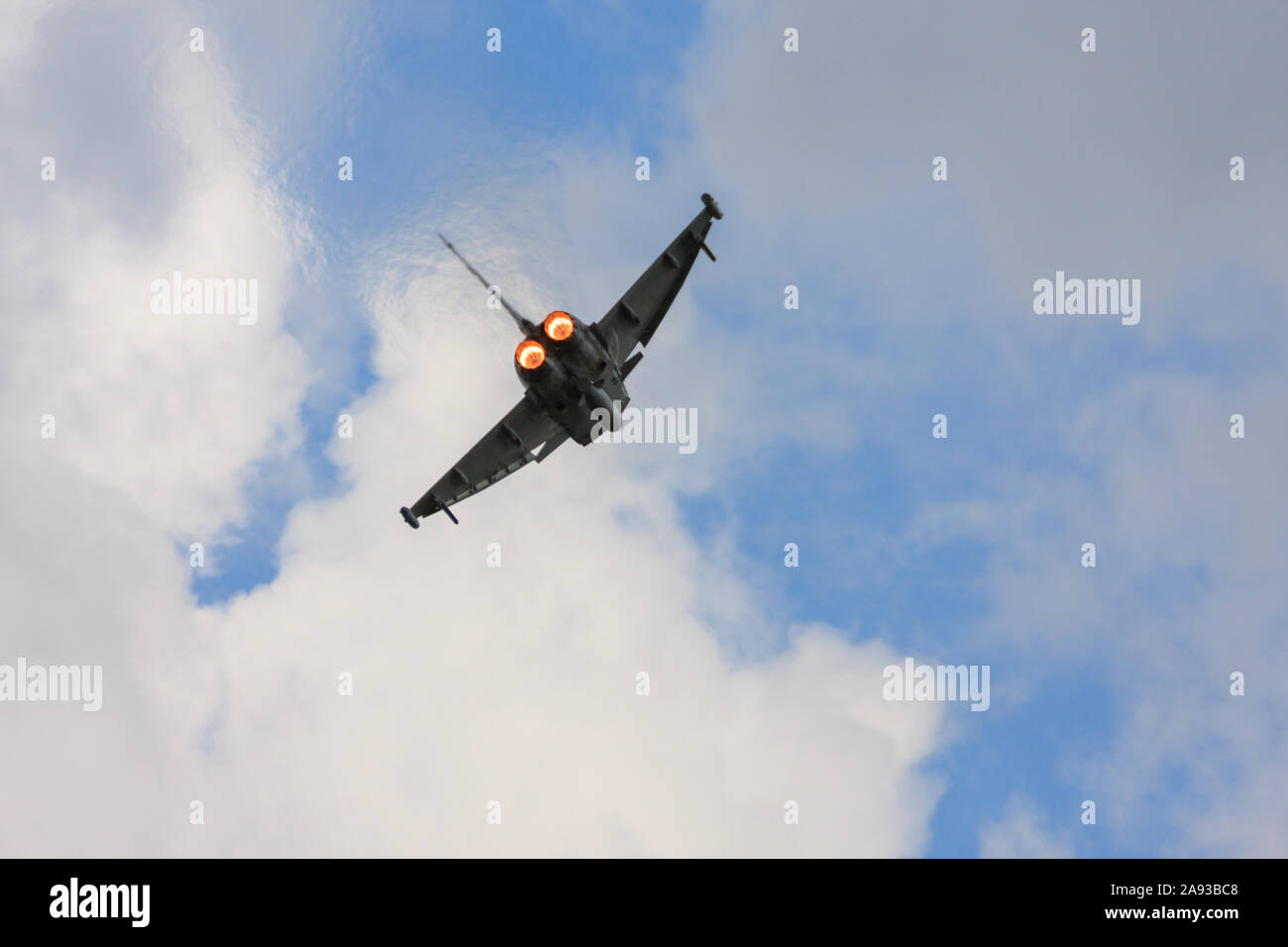 Rear view of an airborne RAF Typhoon multirole jet fighter, showing the engines re-heat (afterburners) full on. Climbing out against a blue sky. Stock Photo