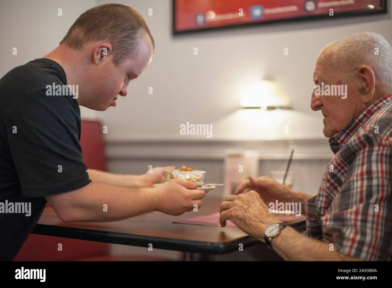 Waiter with Down Syndrome serving food to customer in a restaurant Stock Photo