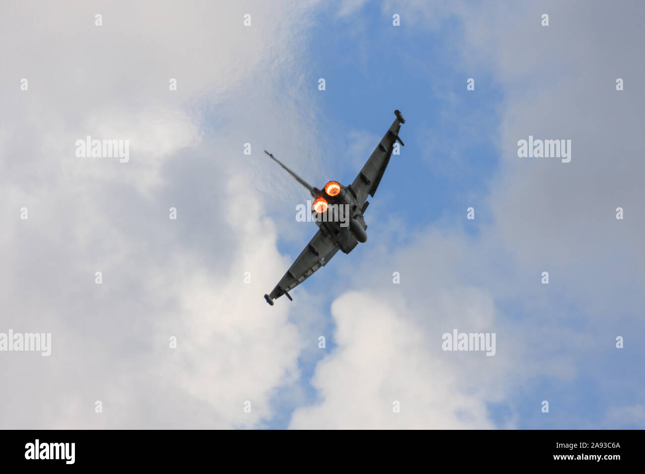 Rear view of an airborne RAF Typhoon multirole jet fighter, showing the engines re-heat (afterburners) full on. Climbing out against a blue sky. Stock Photo