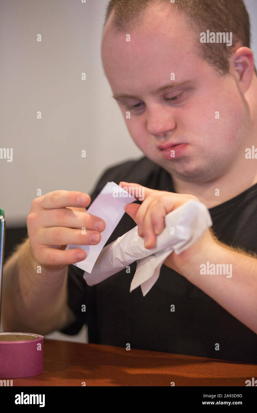 Waiter with Down Syndrome preparing napkin and silver in a restaurant Stock Photo