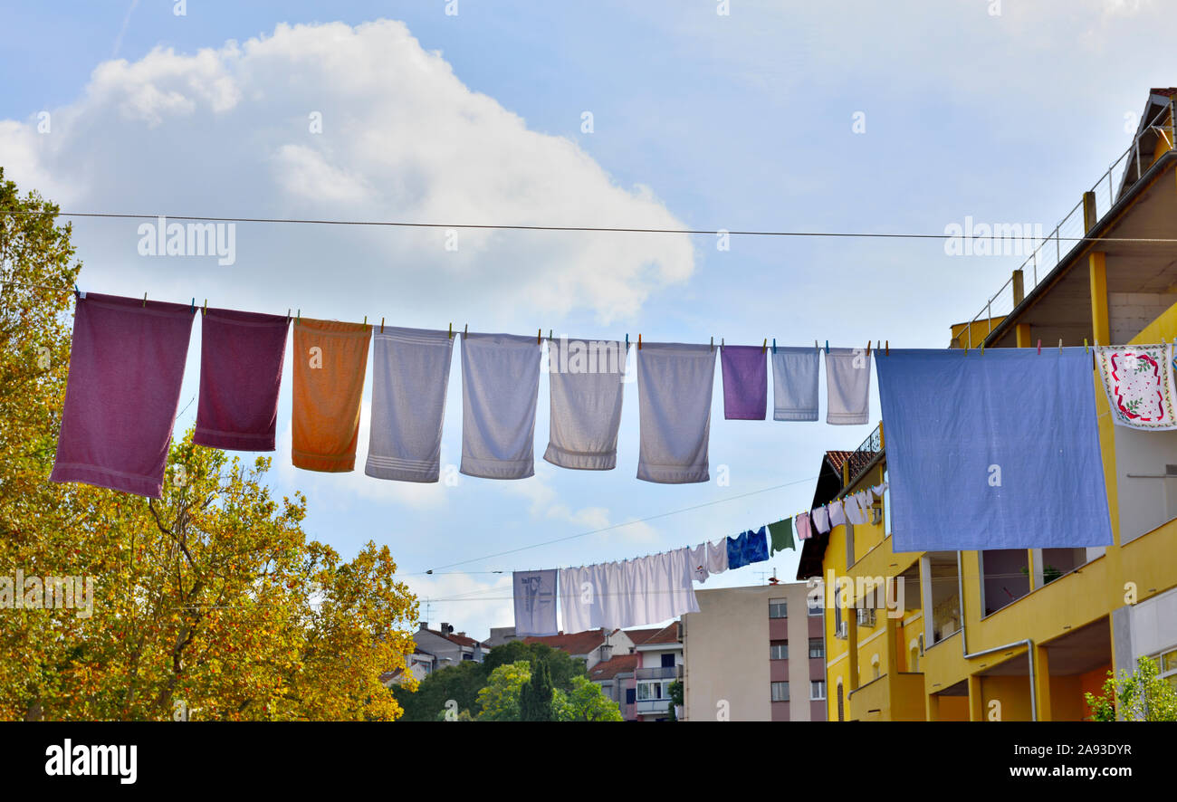 Laundry hanging out to dry on overhead line with blue sky behind Stock Photo