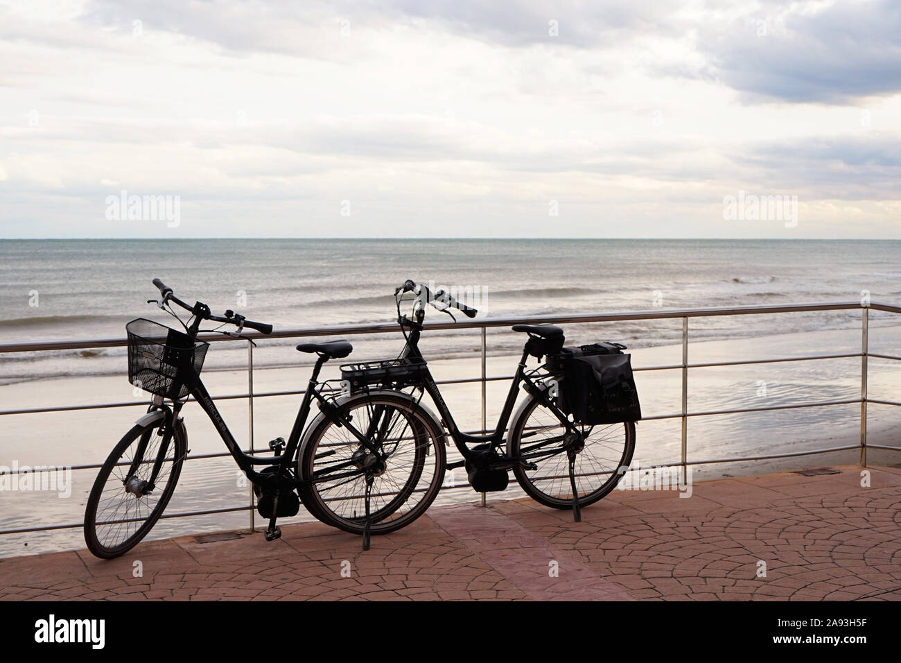 A pair of bicycles parked up together in front of a coastal sea view Stock Photo