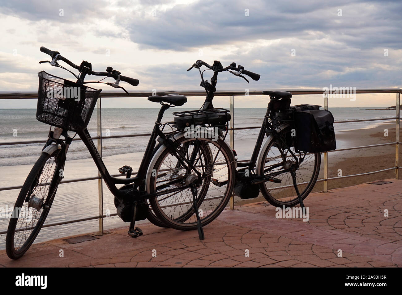 A pair of bicycles parked up together in front of a coastal sea view Stock Photo