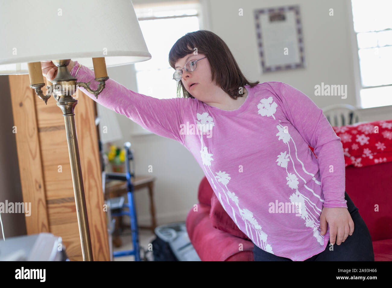 Girl with Down Syndrome turning on the light in her living room Stock Photo