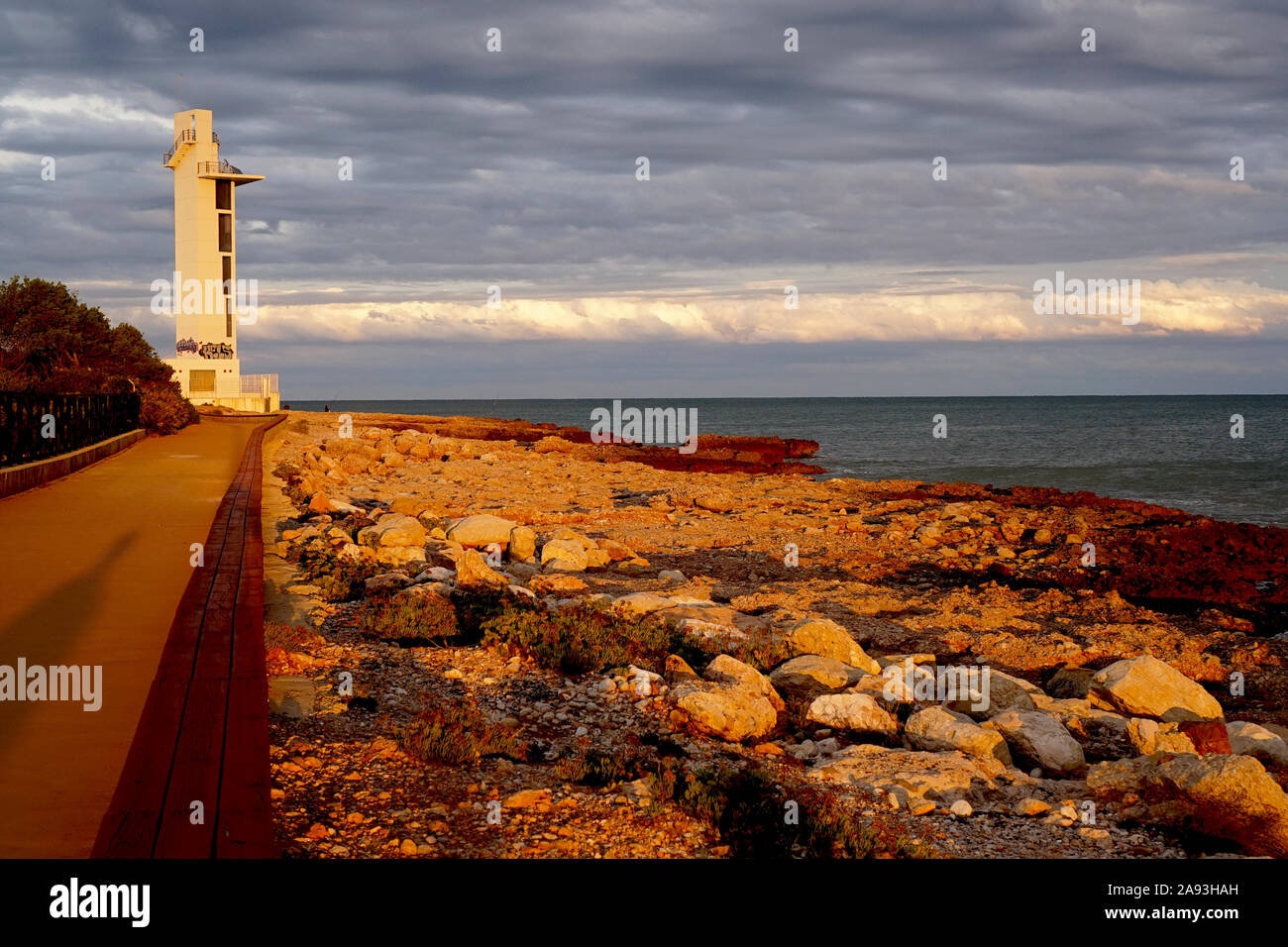 Coastal view of a lighthouse lit by the sunset Stock Photo