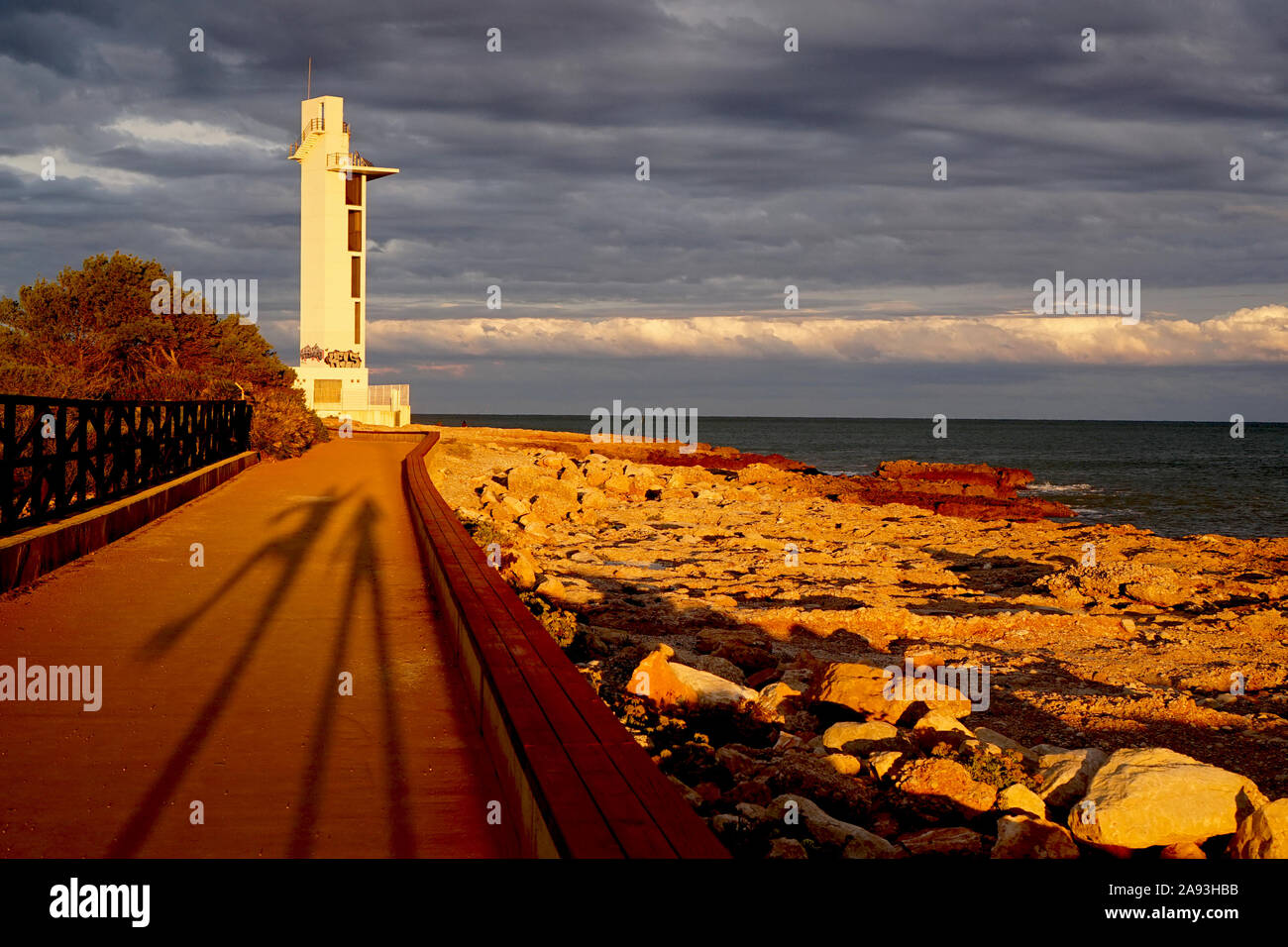 Shadow figures of a couple at sunset by a coastal scene with lighthouse Stock Photo