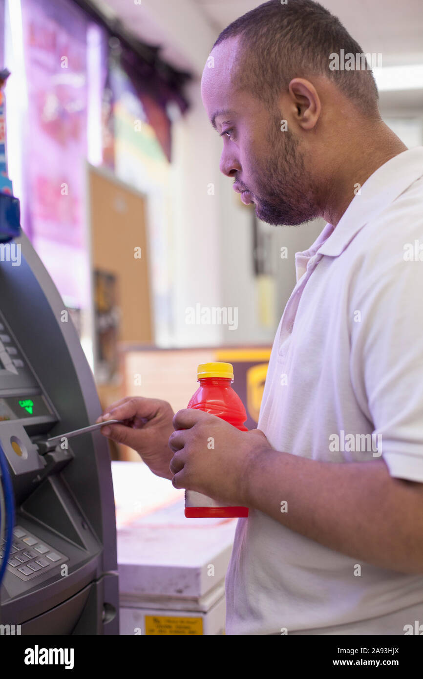 Man with Down Syndrome using a bank ATM Stock Photo