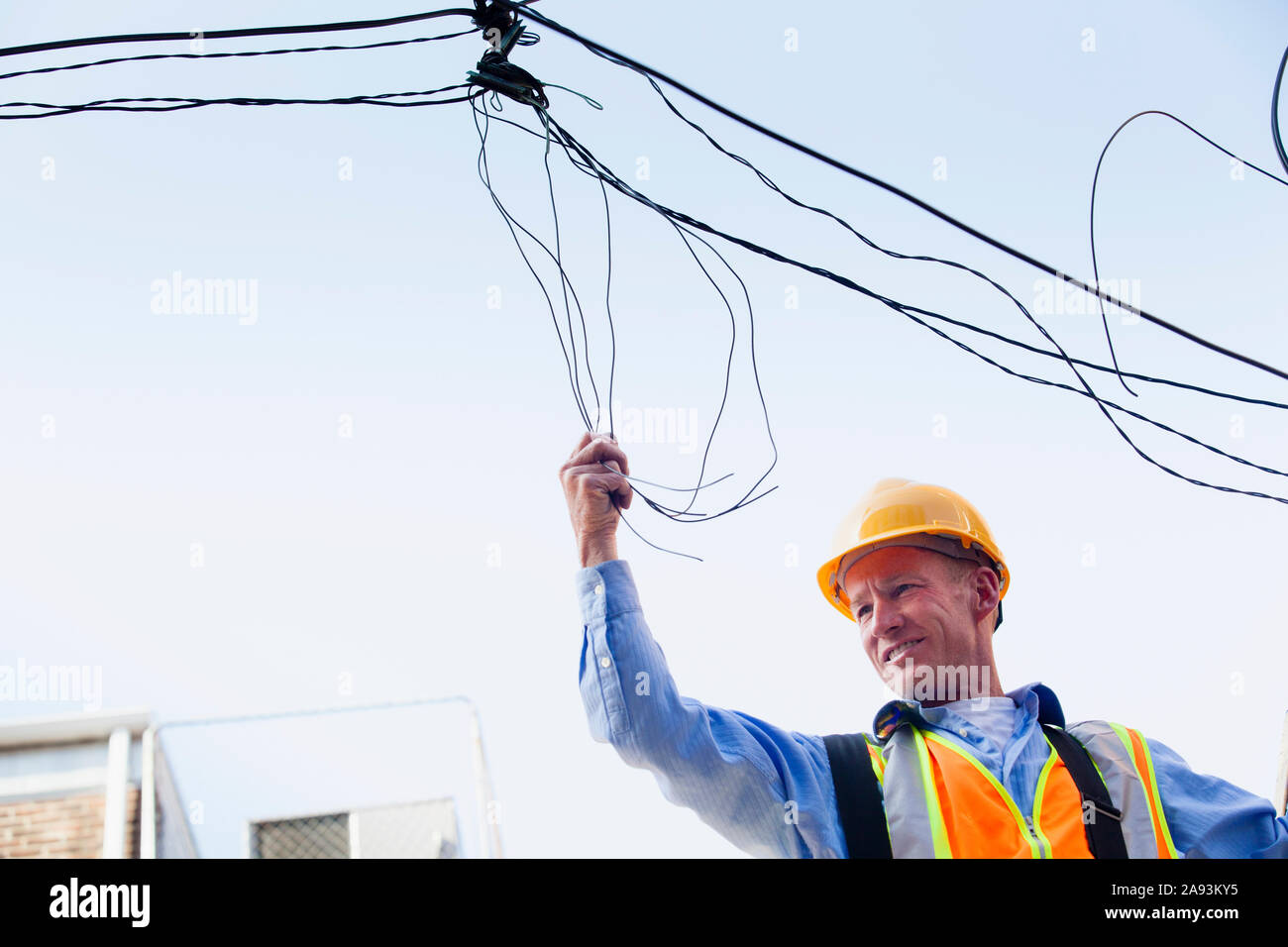 Cable lineman on ladder fixing dangling wires Stock Photo Alamy