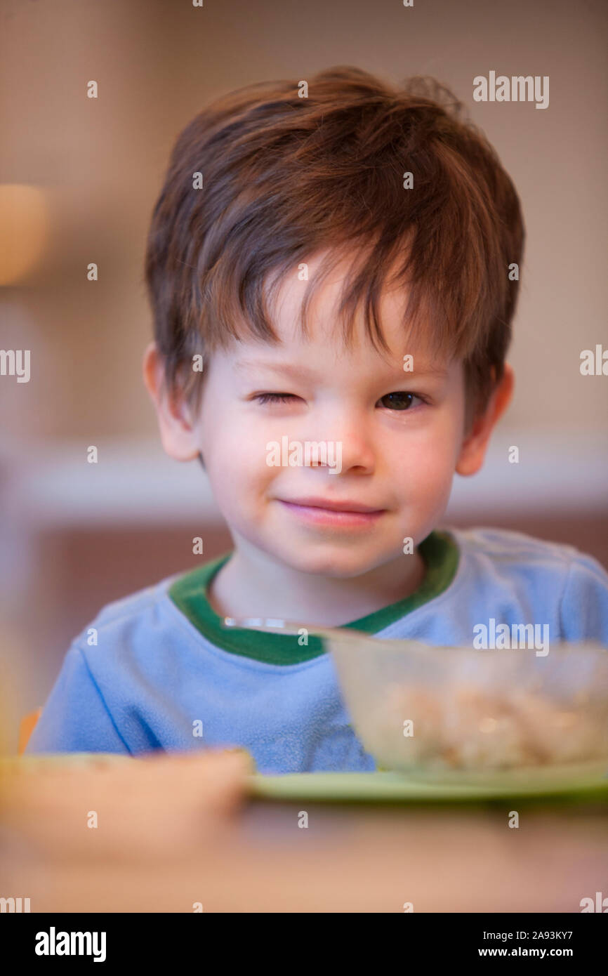 Little boy sitting at a breakfast table with a bowl of cereal Stock Photo