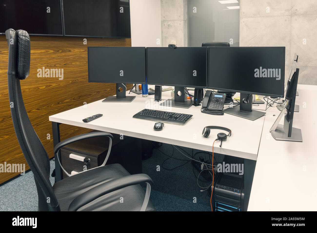 dvelopers desktop with three black monitors in office. empty chair Stock Photo