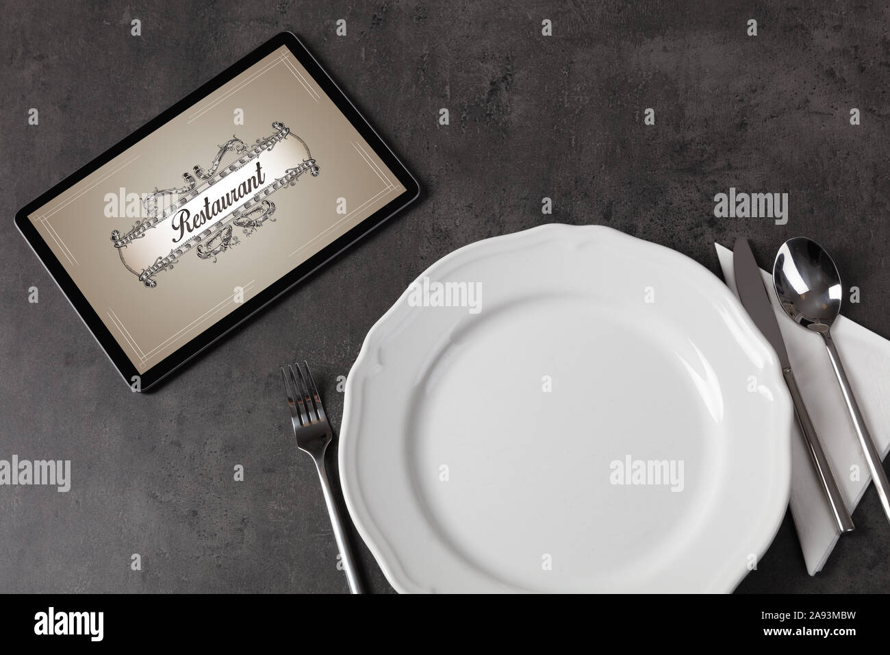 Tablet with stylish restaurant logo and laid table Stock Photo