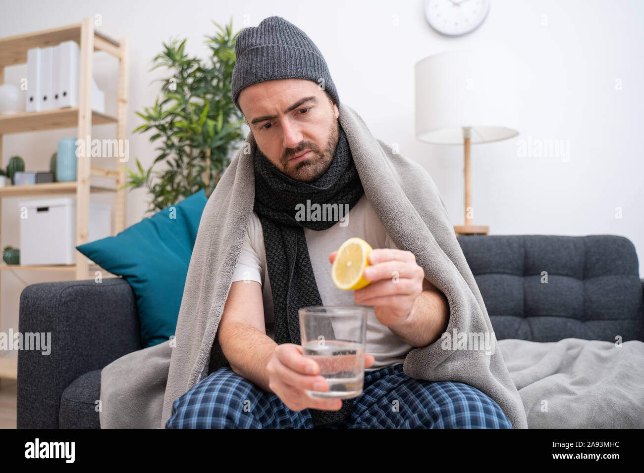 Man wrapped in plaid lying on the sofa feeling sick illness at home Stock Photo