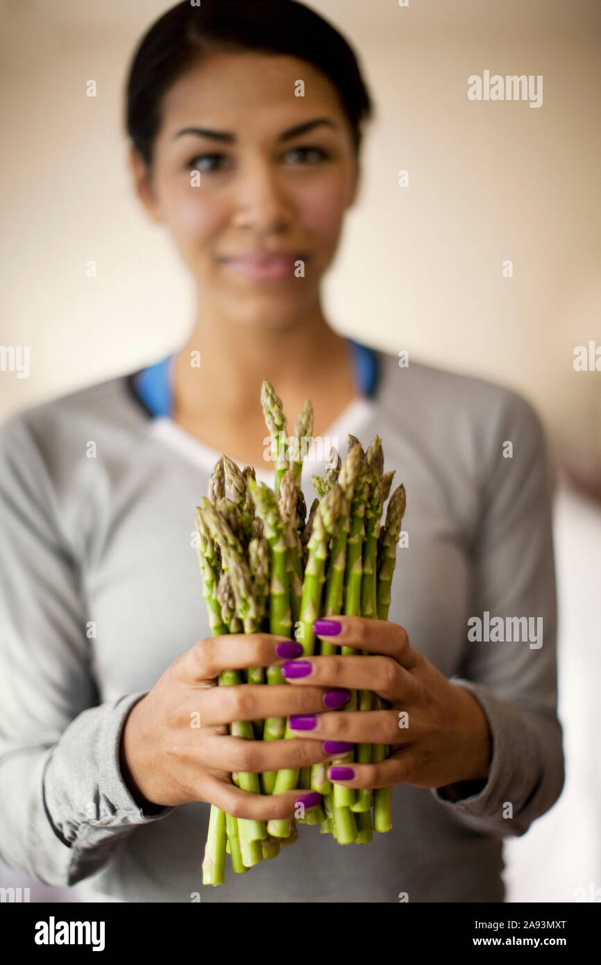 Portrait of a young woman holding a bunch of fresh asparagus Stock Photo
