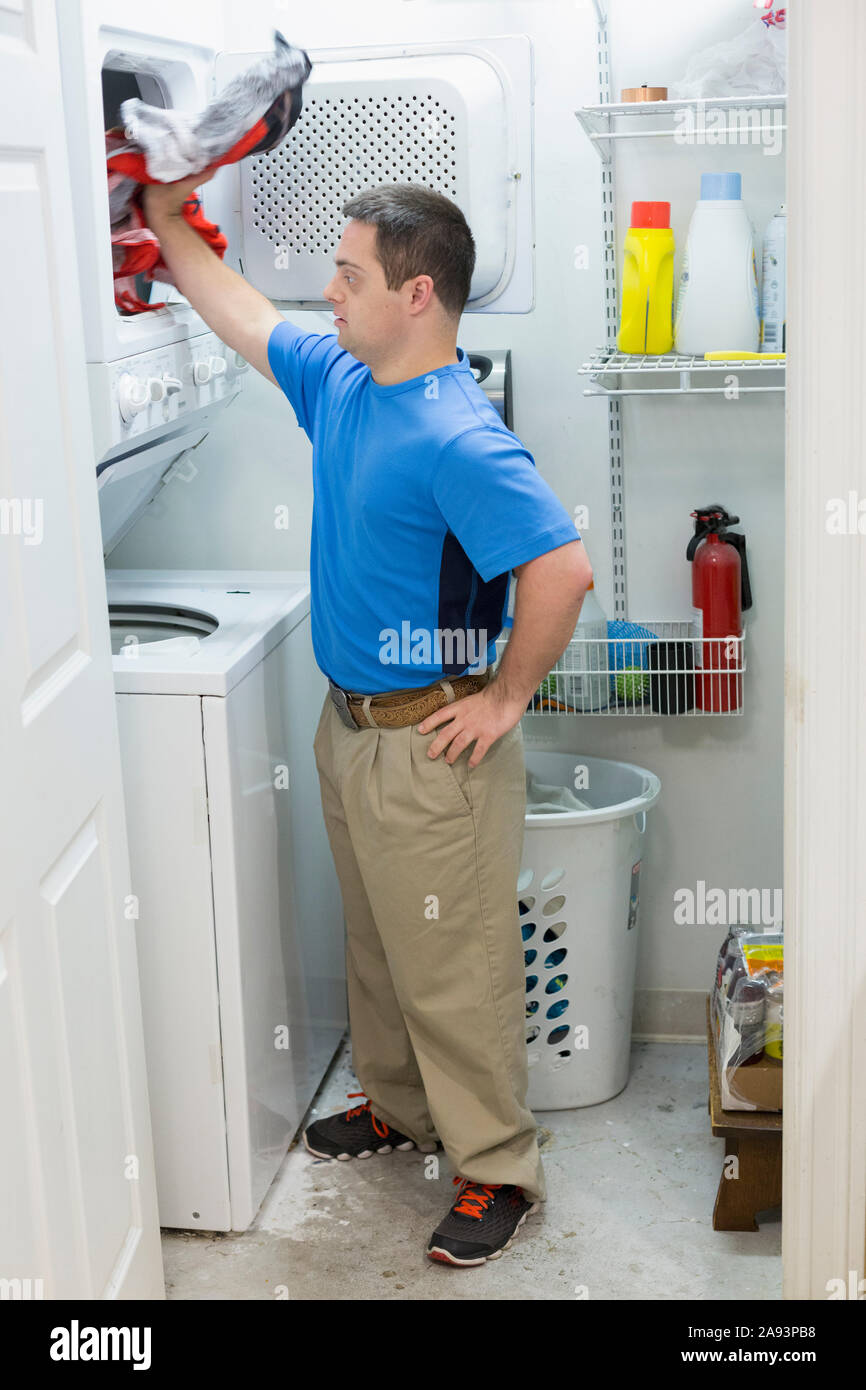 Man with Down Syndrome standing in laundry room Stock Photo