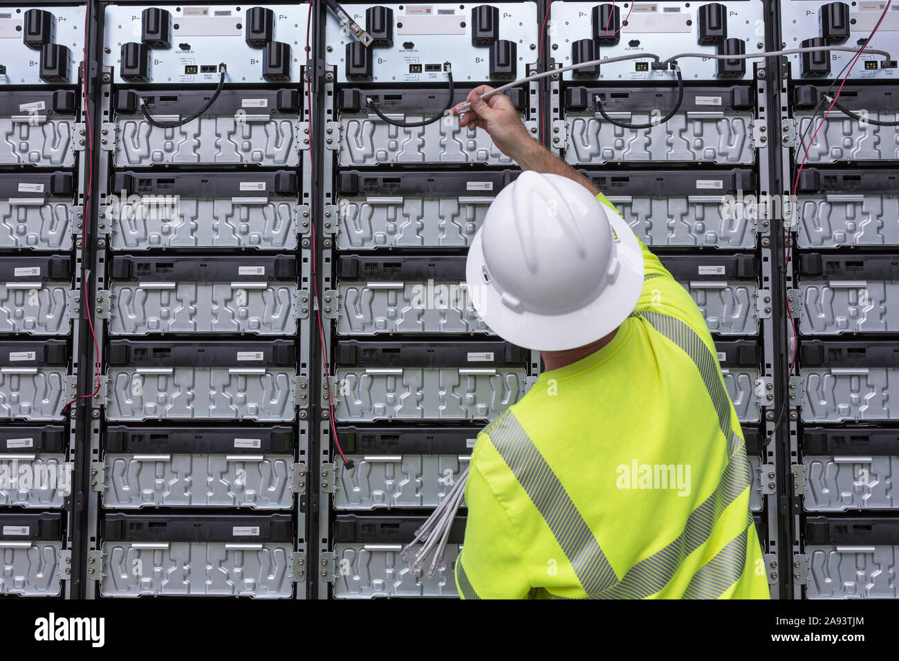 Engineer connecting energy storage batteries for back up power to an electric power plant Stock Photo