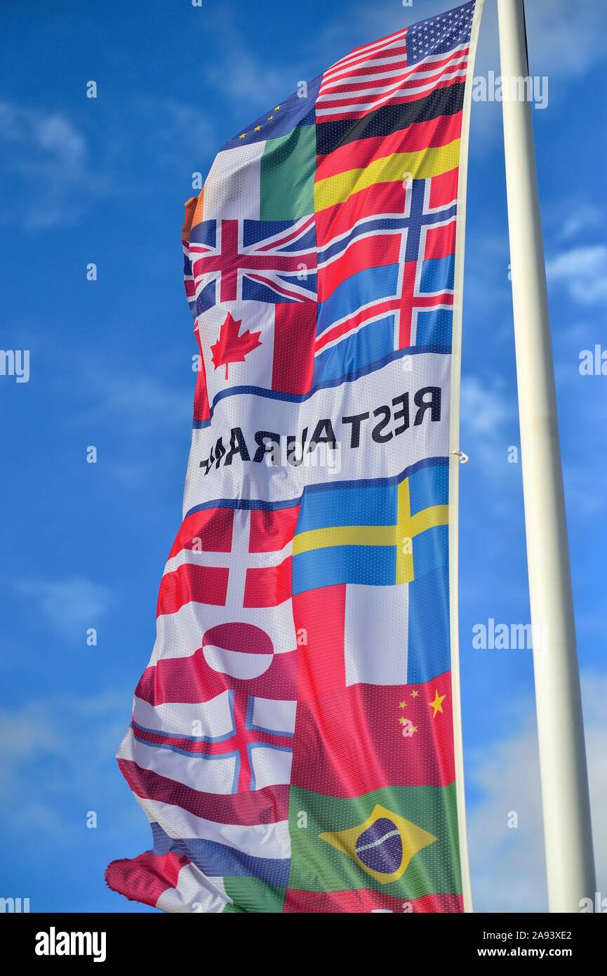 Vik, Iceland. A banner with an assortment of national flags on a large flagpole used to attract tourists from a variety of countries. Stock Photo