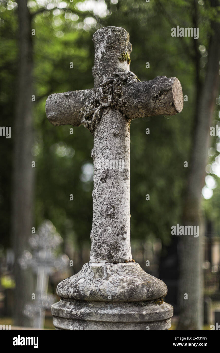 White cross on gravestone, covered with lichen Stock Photo