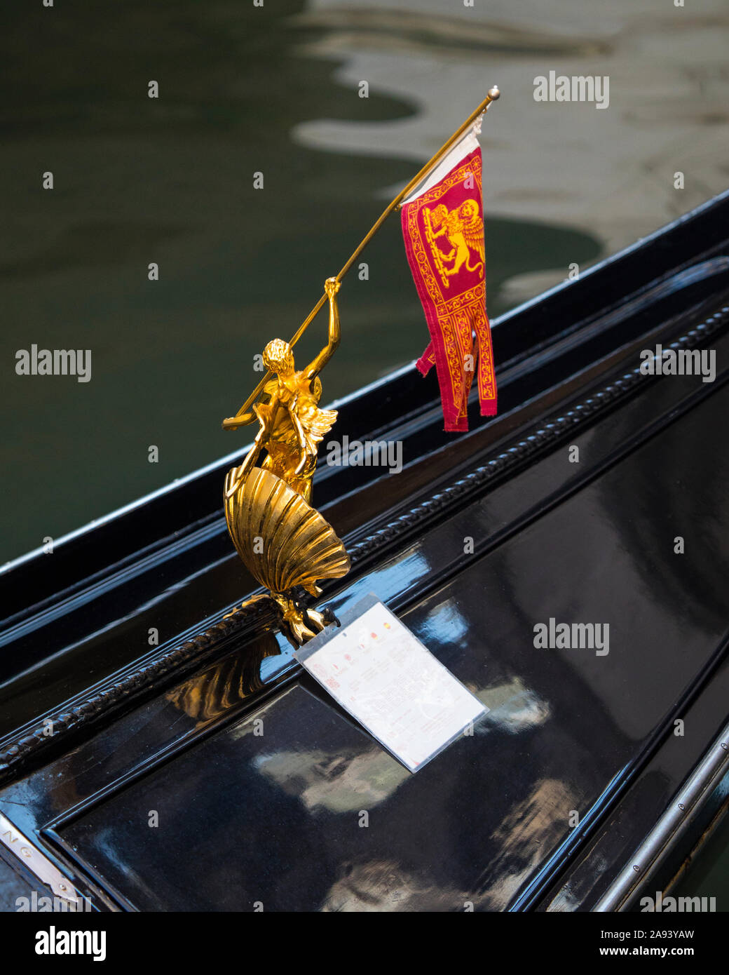 Venice, Italy - July 20th 2019: Close-up detail of a golden sculpture decoration holding the Venetian flag on a Gondola in Venice, Italy. Stock Photo
