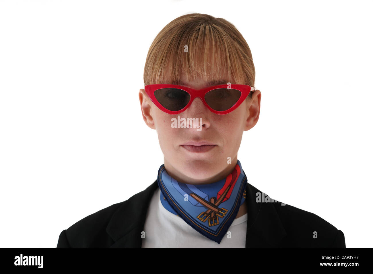 headshot blonde woman with neutral expression wearing red cat-eye sunglasses and a silk neckerchief, white background Stock Photo