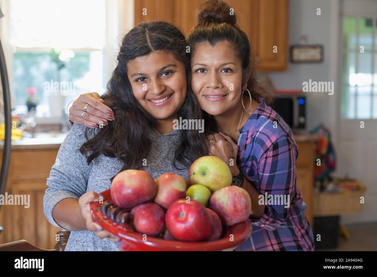 Teenage girl who has intellectual disability holding apples with her mother Stock Photo