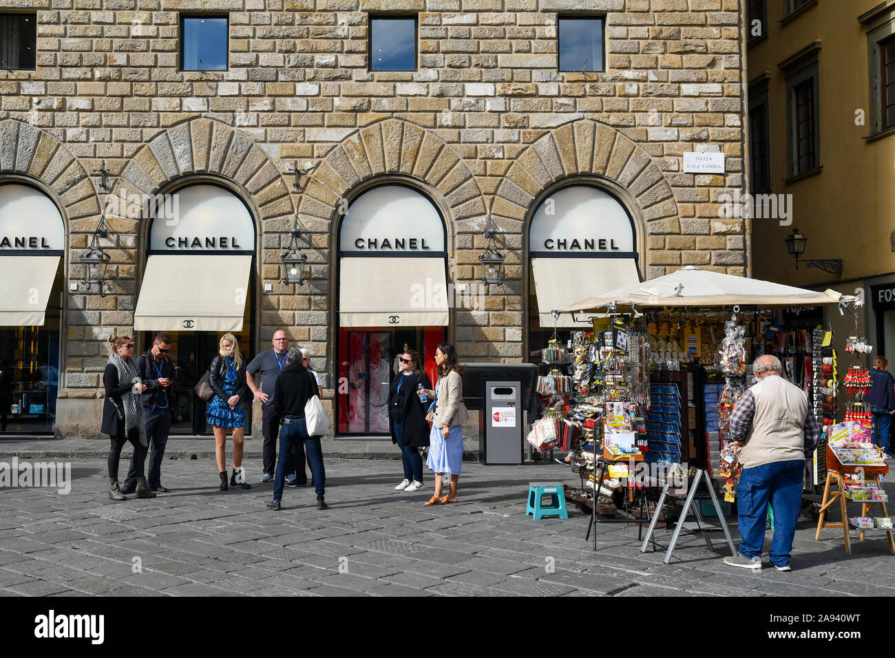 Souvenir stall with street vendor in front of the Chanel fashion boutique in Signoria Square in the historic centre of Florence, Tuscany, Italy Stock Photo
