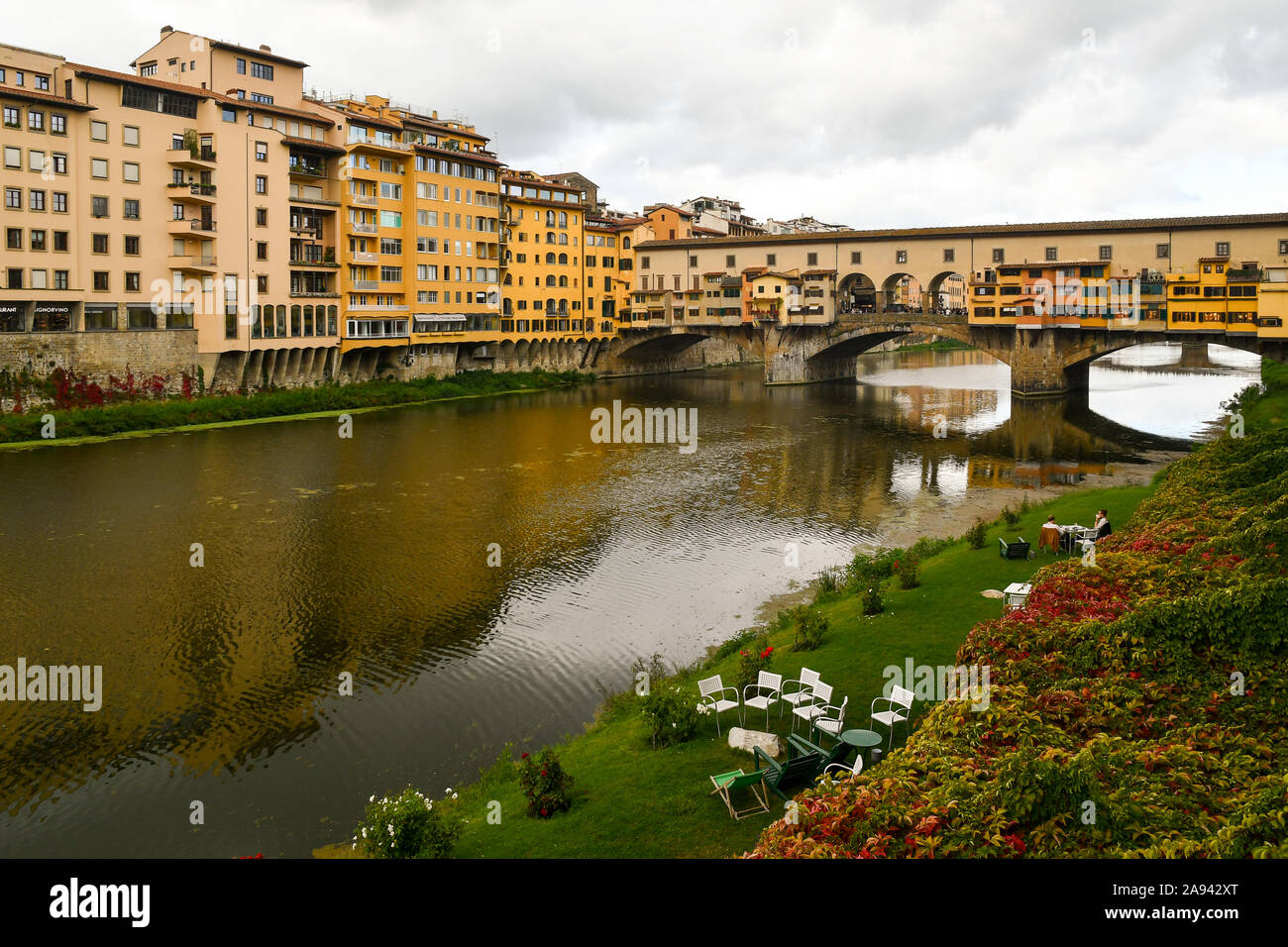 Scenic view of Arno River waterfront ('Lungarno'), with Ponte Vecchio medieval bridge and a garden in autumn, Florence, Tuscany, Italy Stock Photo