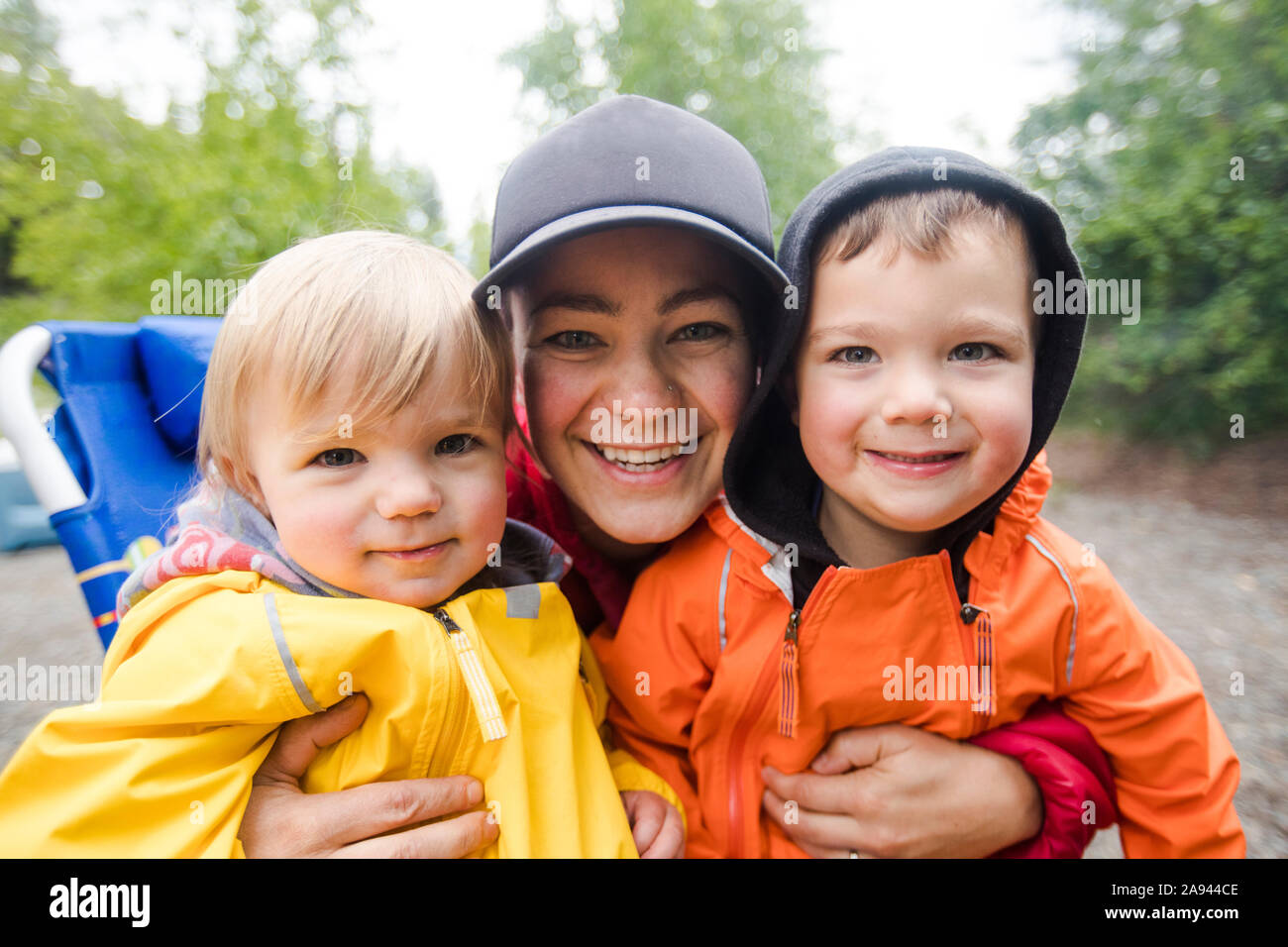 portrait of mother with her two kids with rain jackets on. Stock Photo