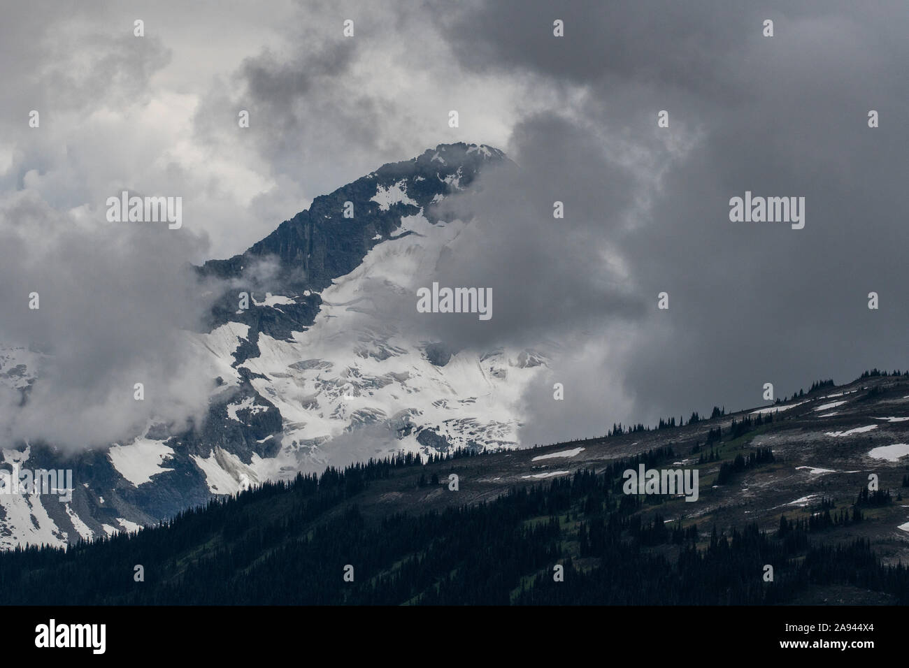 Scenic view of a mountain peak shrouded in clouds on a stormy summer day in British Columbia. Stock Photo