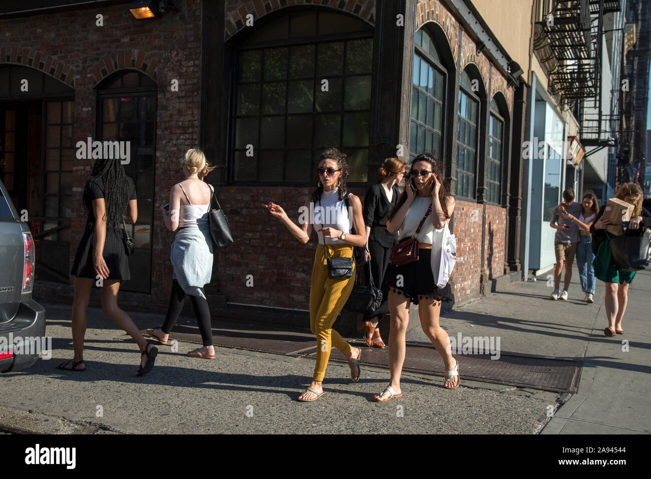 Young women walk on sidewalk in New York's Bowery, Lower Mnahattan. Stock Photo