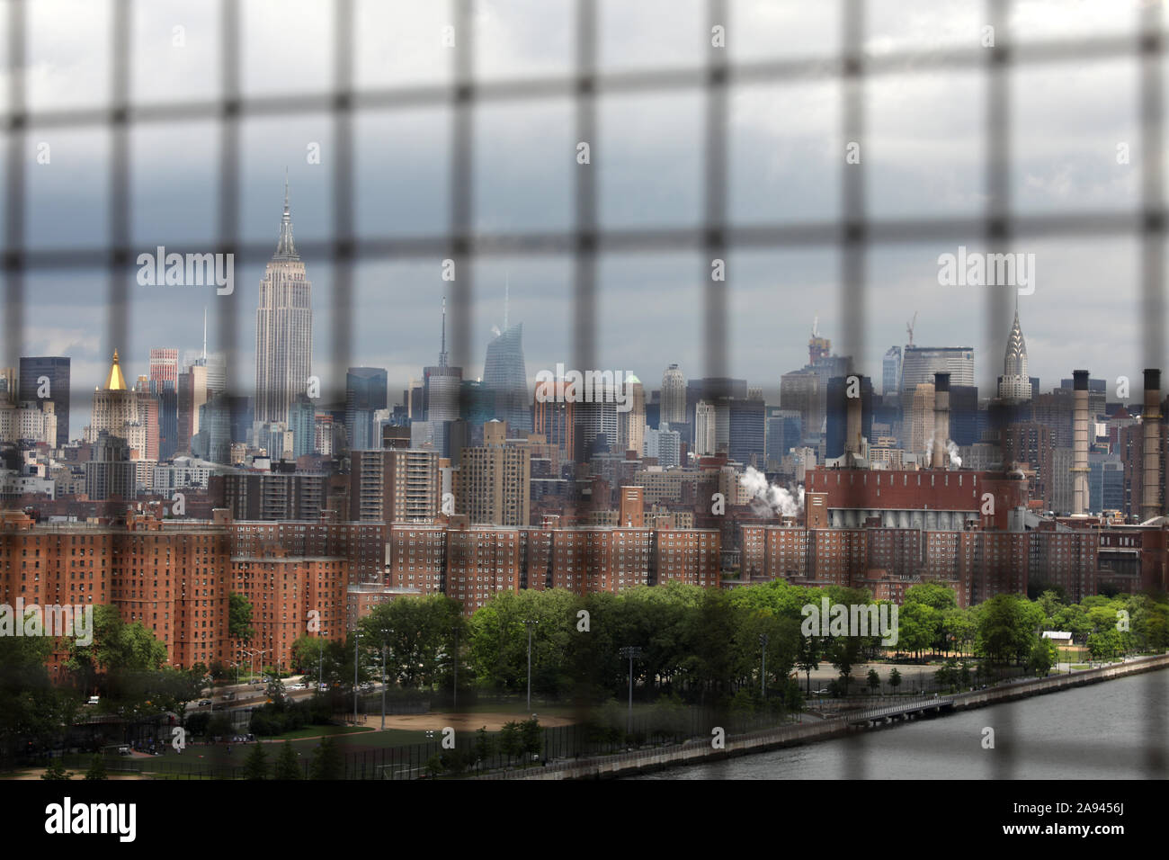 View of Manhattan Skyline from Brooklyn Bridge through safety wire Stock Photo