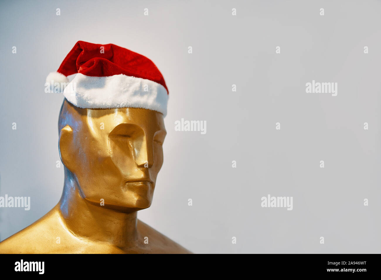 Bishkek, Kyrgyzstan - December 21, 2018: The man in the Christmas hat. A Golden statue of Oscar stands in a Christmas hat. Stock Photo