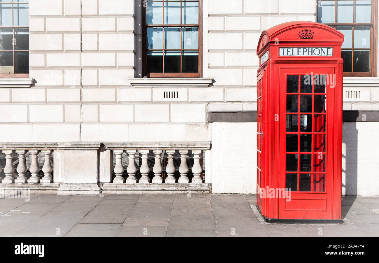 London telephone box. Traditional old-style UK red phone box set against a beige government building in central London. Stock Photo