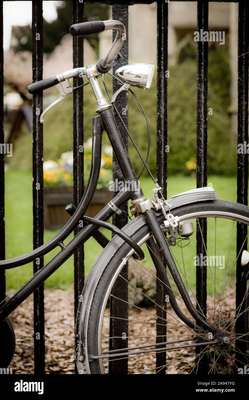 Locked bicycle. An old fashioned bicycle with a retro dynamo locked to some railings by a Cambridge University college. Stock Photo