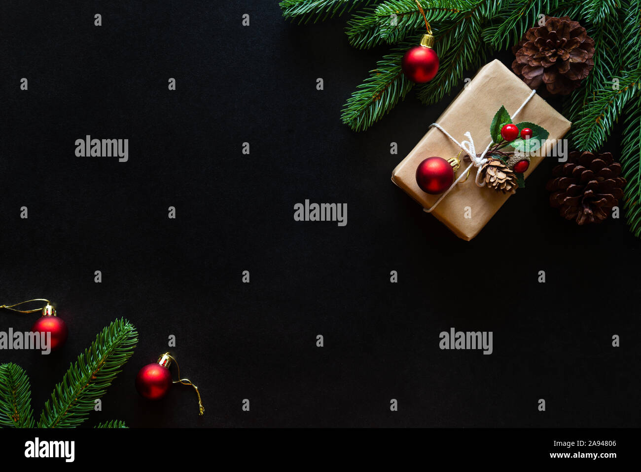 Holiday Christmas card background with festive decoration ball, stars, snowflakes, gift box, pine cones on a black background from Flat lay, top view. Stock Photo