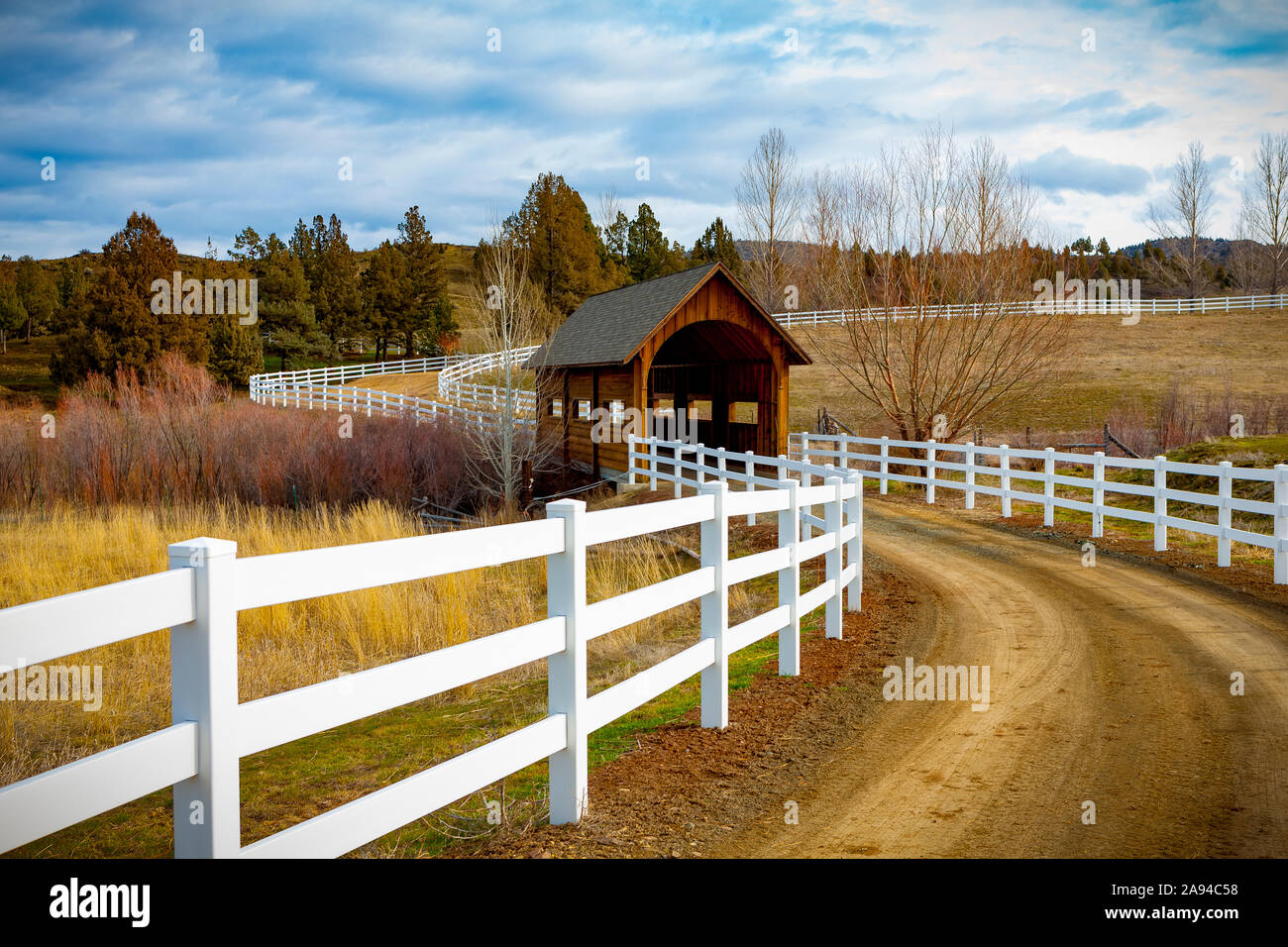 Covered bridge over a river in the countryside with dirt road; Oregon, United States of America Stock Photo