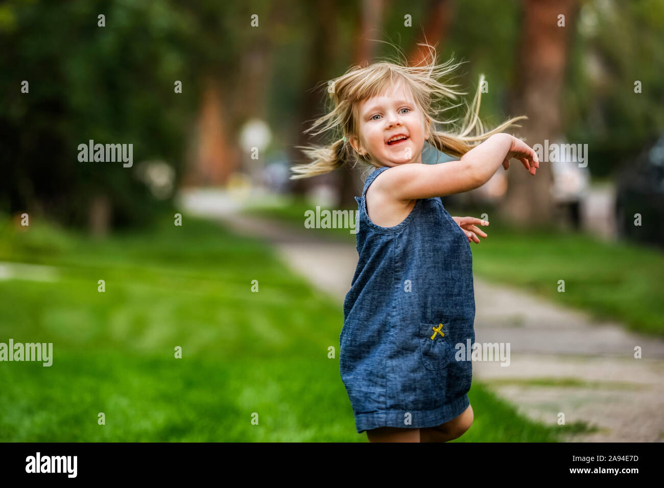 Young girl in pigtails moves during playtime in her neighbourhood; Edmonton, Alberta, Canada Stock Photo