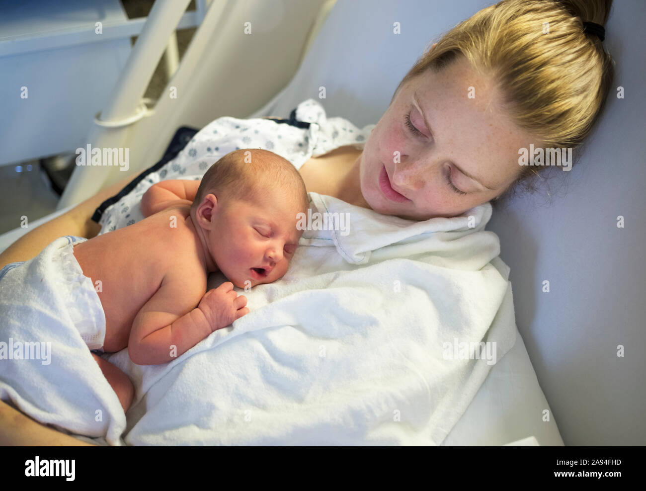 Newborn baby sleeping on mother s chest in a hospital bed