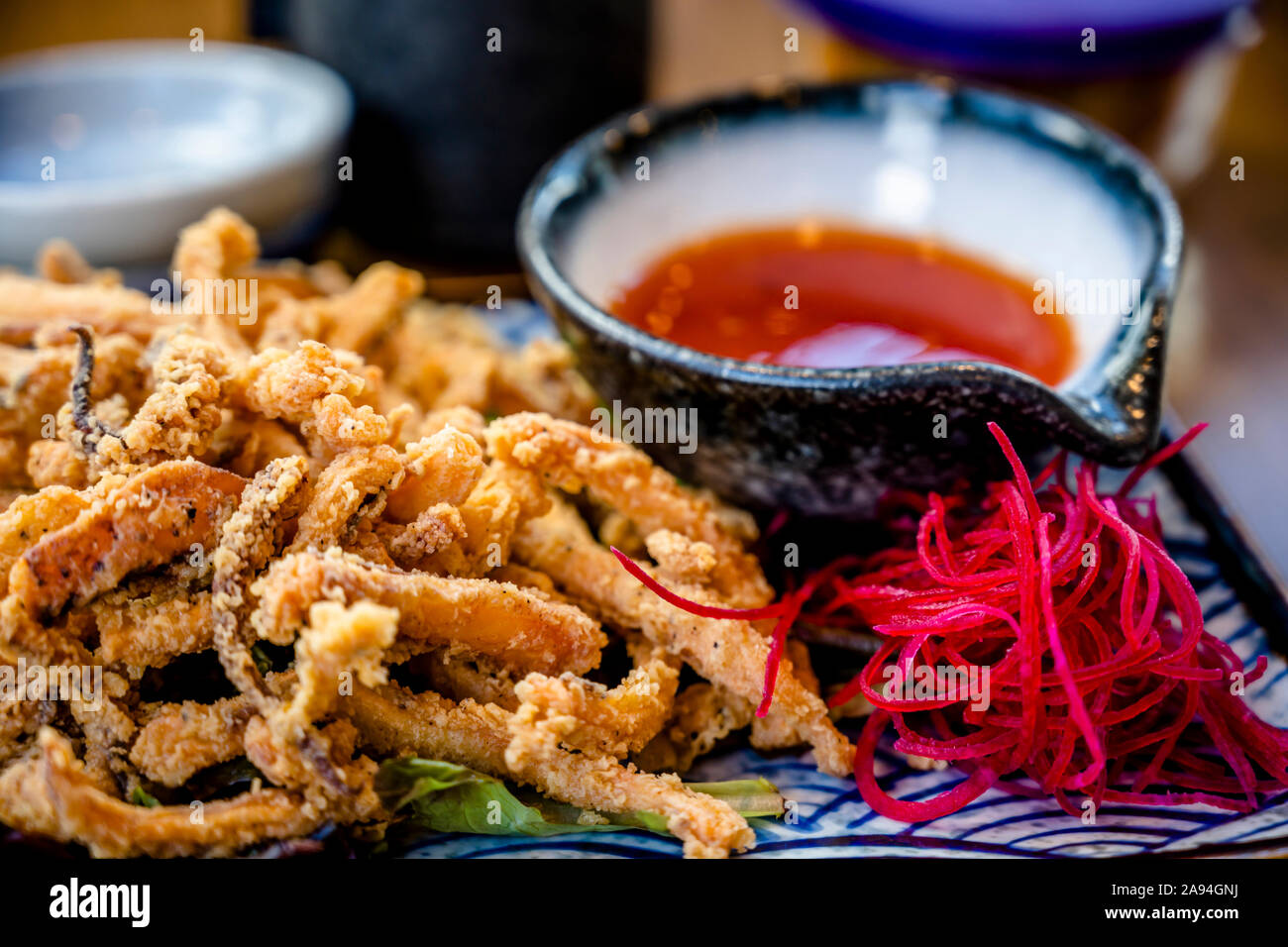 Plates with various kinds of expertly cooked fried squid with spices and hot sauces are displayed on dining table to enjoy delicious and dietary natur Stock Photo