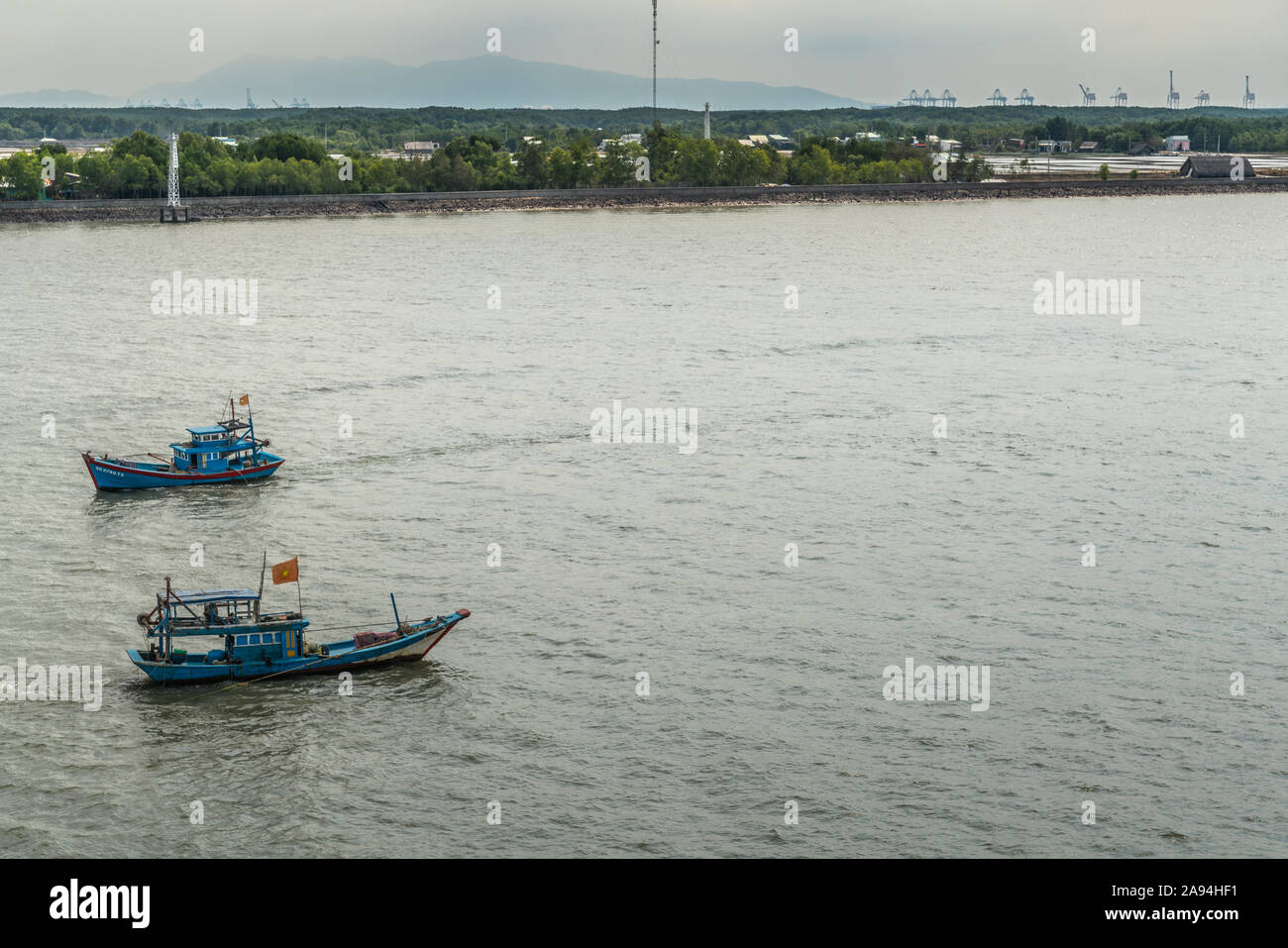 Long Tau River, Vietnam - March 12, 2019: At Thieng Lieng just up from mouth of river: Two traditional blue fishing vessels cross each other from and Stock Photo