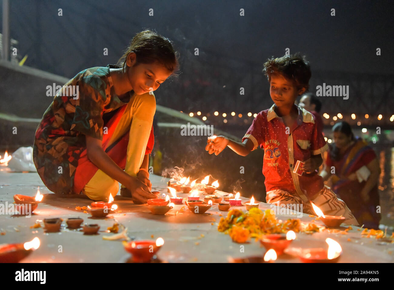 Kolkata, India. 12th Nov, 2019. Children lighting up the steps of the ghat of Ganges which is decorated with earthen lamps during Dev deepawali.Dev Deepawali is observed on the full moon day (Purnima) in the month of Kartik after fourteen days of Diwali. Credit: SOPA Images Limited/Alamy Live News Stock Photo