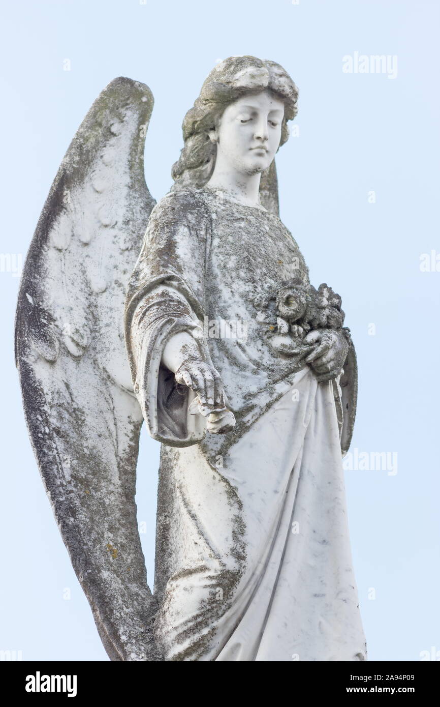 close up image of an angel figurine against a pale sky background. Stock Photo